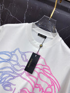 White T-shirt with blue and pink Medusa graphic and hanging Versace tag at collar.