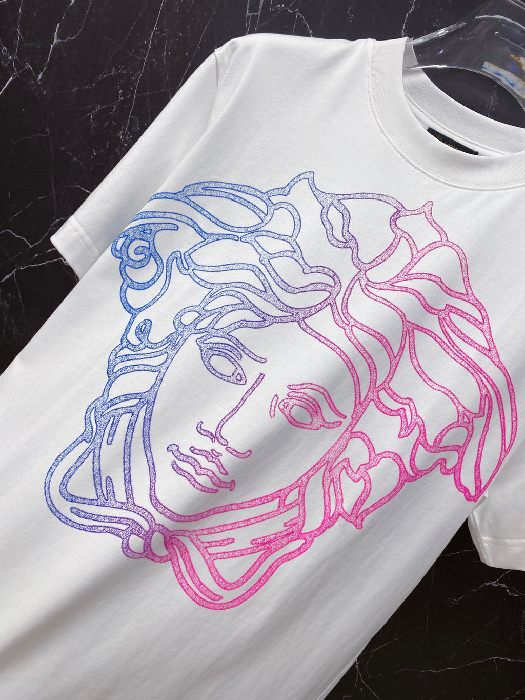 White T-shirt with blue and pink Medusa-style face graphic, crew neck.
