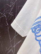 White T-shirt sleeve with partial blue and pink graphic print.