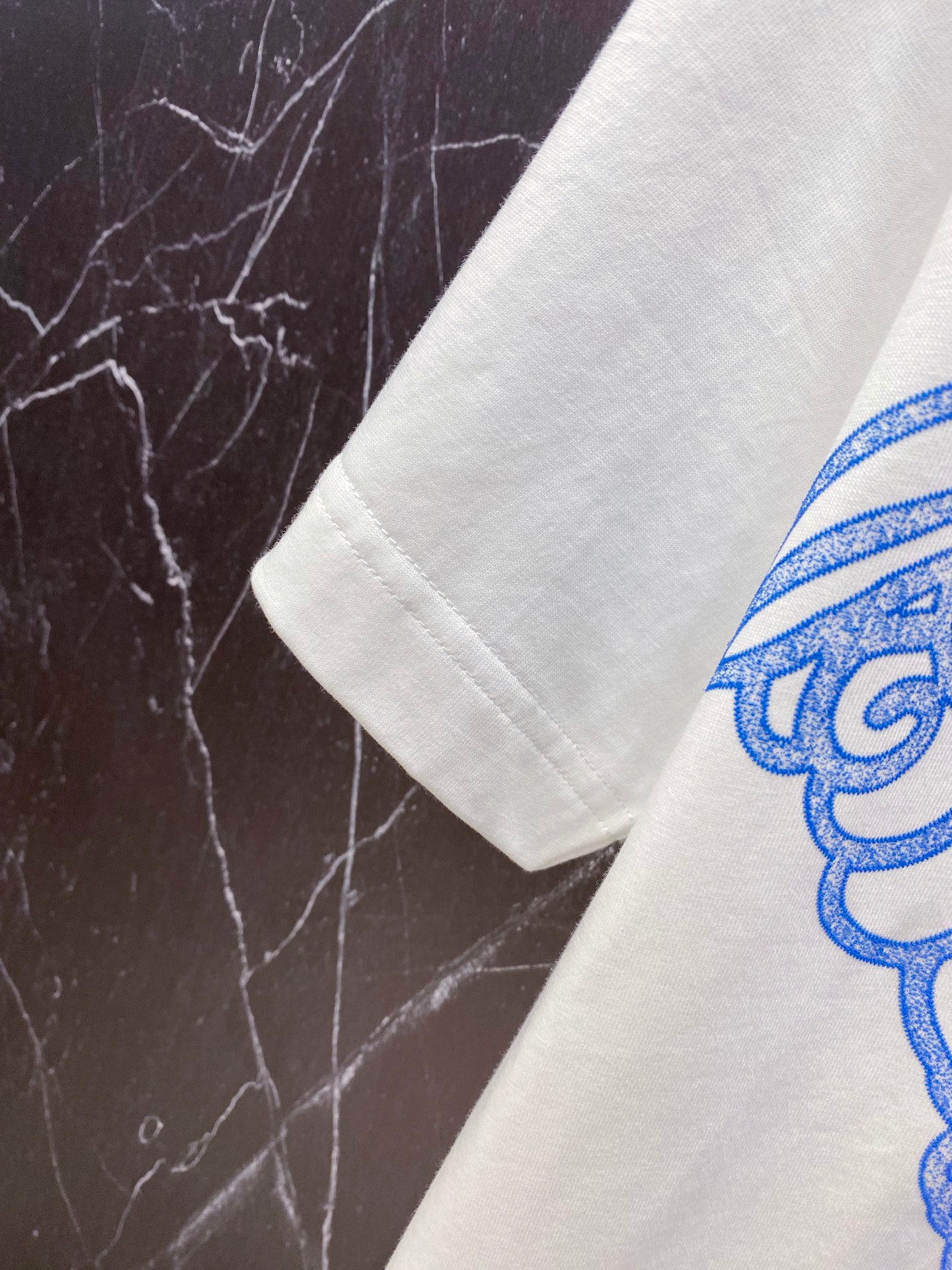 White T-shirt sleeve with partial blue and pink graphic print.