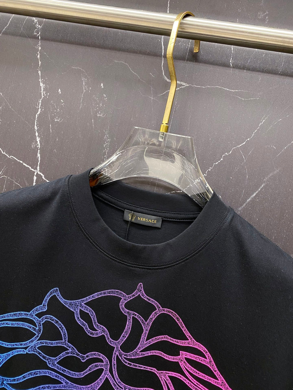 Black T-shirt neckline and neon blue/pink Medusa face graphic