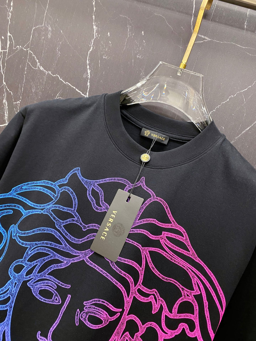 Black graphic T-shirt with neon Medusa line-art and hanging brand tag