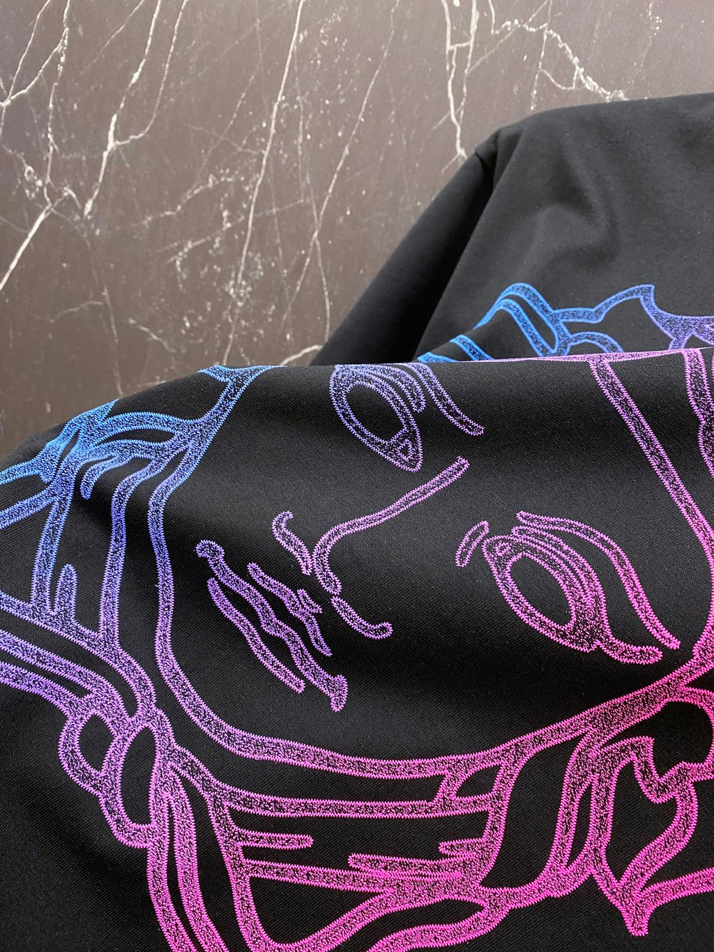 Black T-shirt close-up of neon blue and pink line-art Medusa head