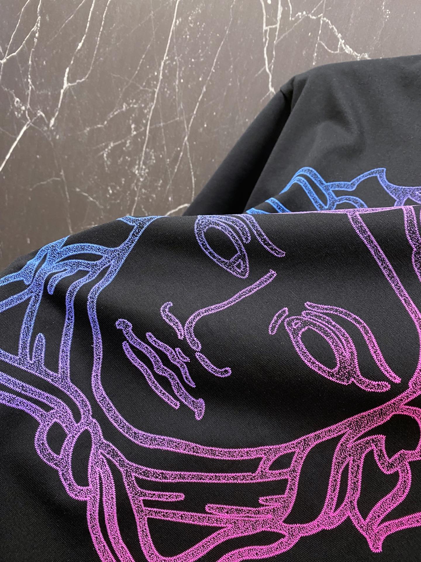 Black T-shirt close-up of neon blue and pink line-art Medusa head