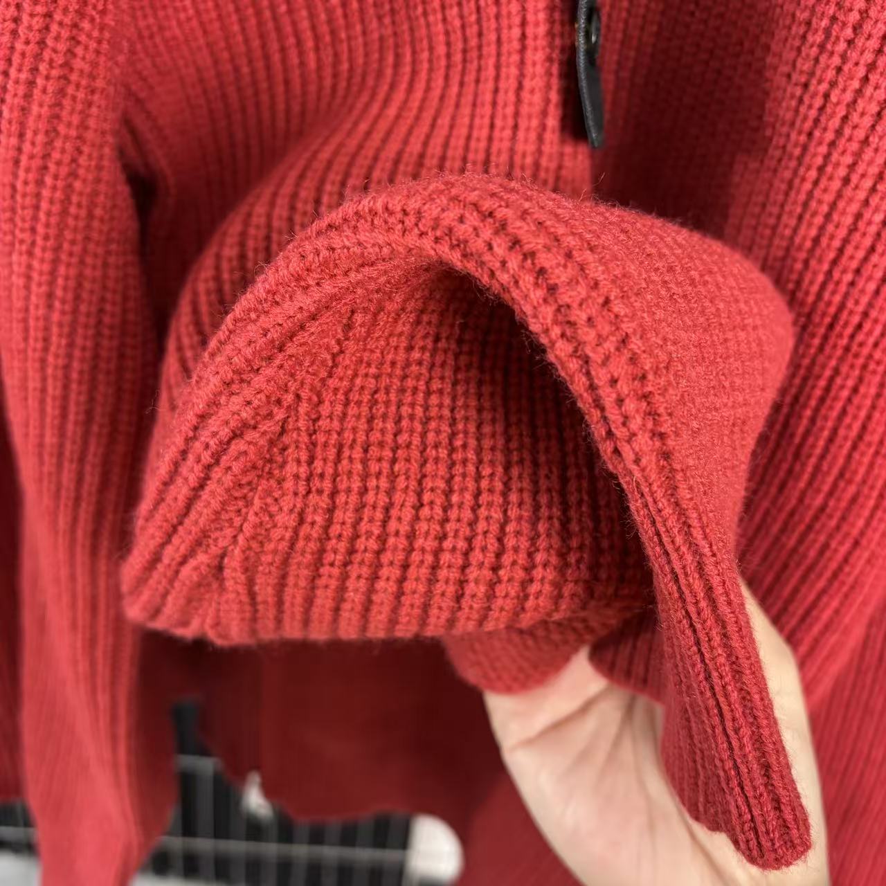 Red knit sweater sleeve and cuff with high collar zipper edge detail