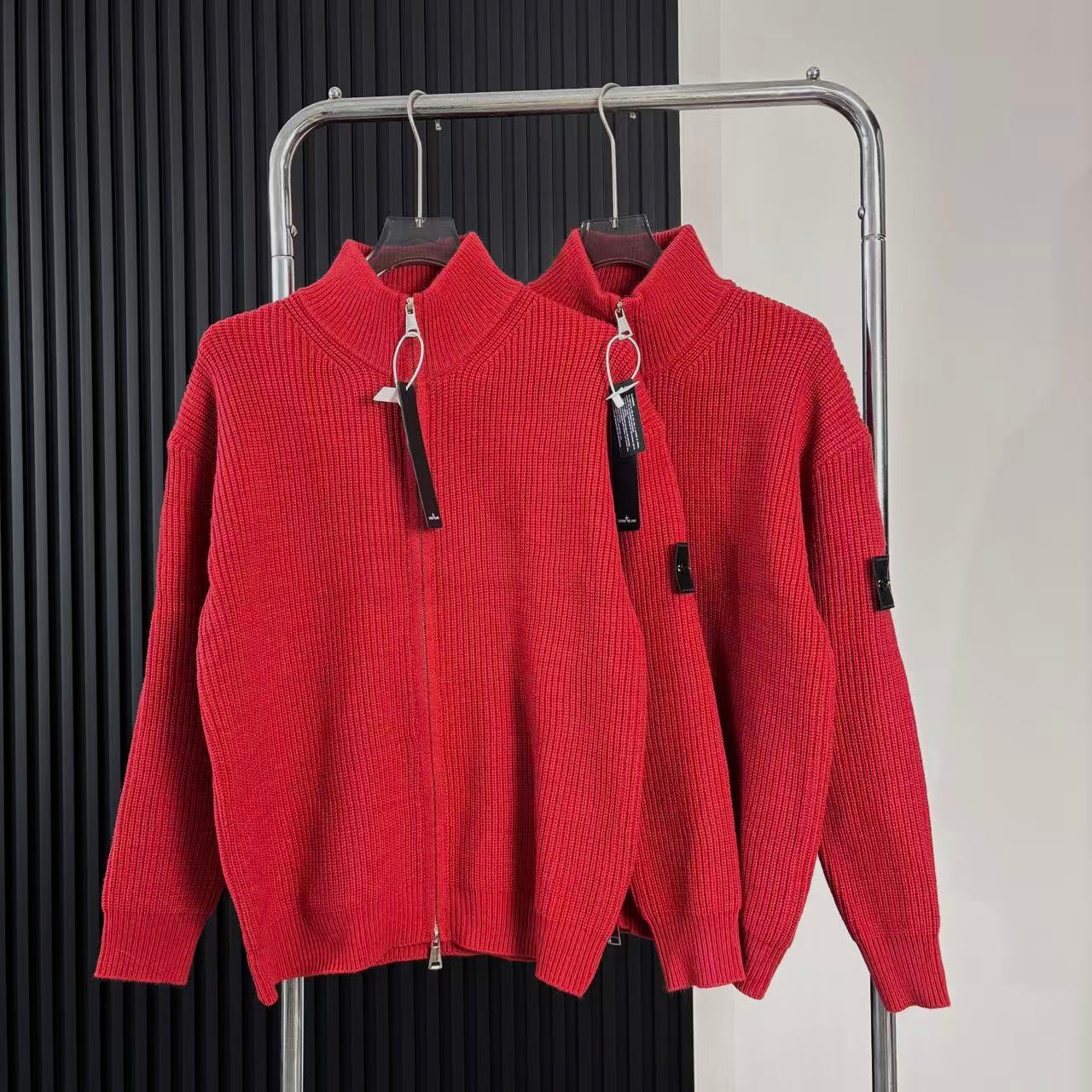 Red knit zip-up sweater with high collar, front zipper, hanging tags on rack