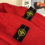 Red knit sweater lying flat with Stone Island branded hang tags near collar