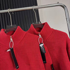 Red knit zip-up sweater close-up with high collar and hanging zipper pull tags