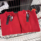 Red knit zip-up sweater pair with high collars and hang tags on metal stand