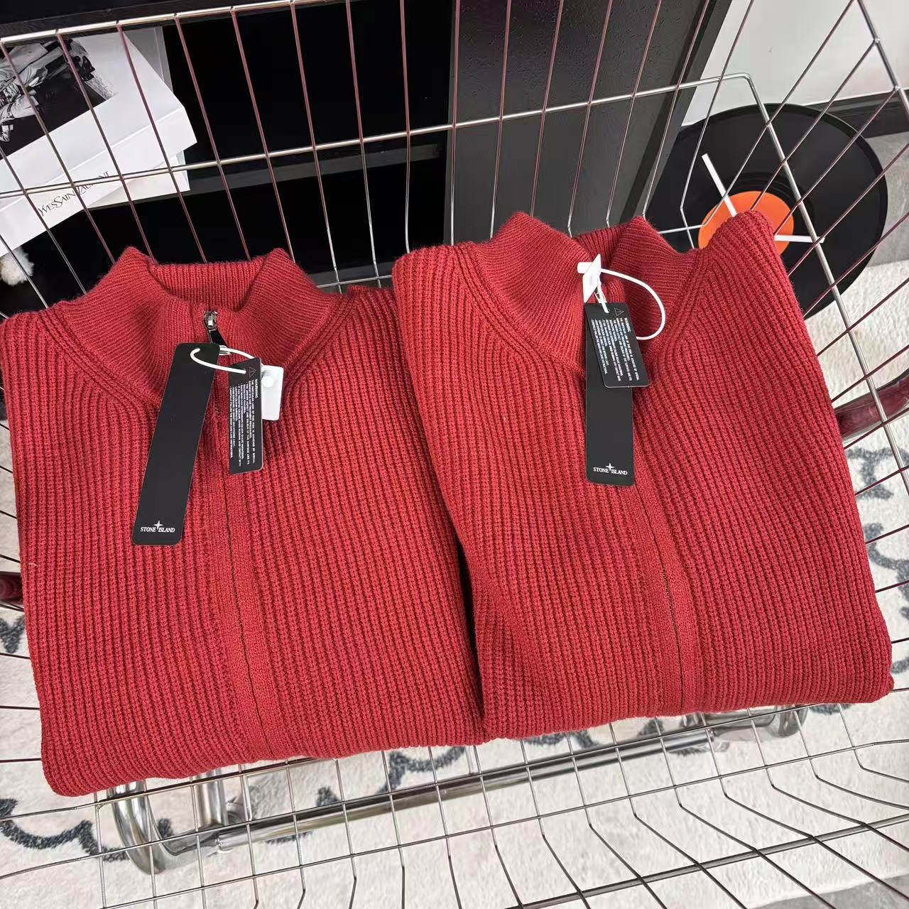Red knit zip-up sweater pair with high collars and hang tags on metal stand