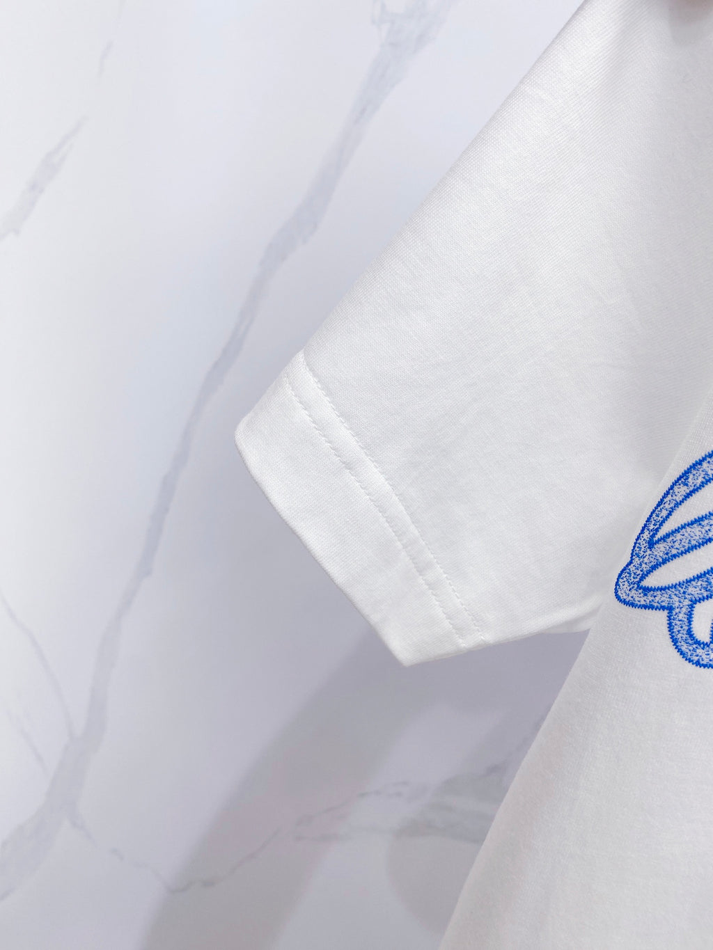 White short-sleeve T-shirt sleeve with partial blue graphic print