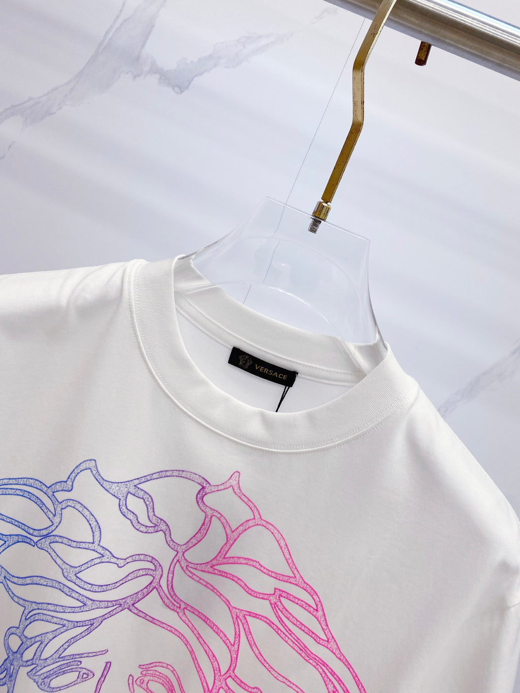 White crewneck T-shirt with blue and pink Medusa graphic at chest