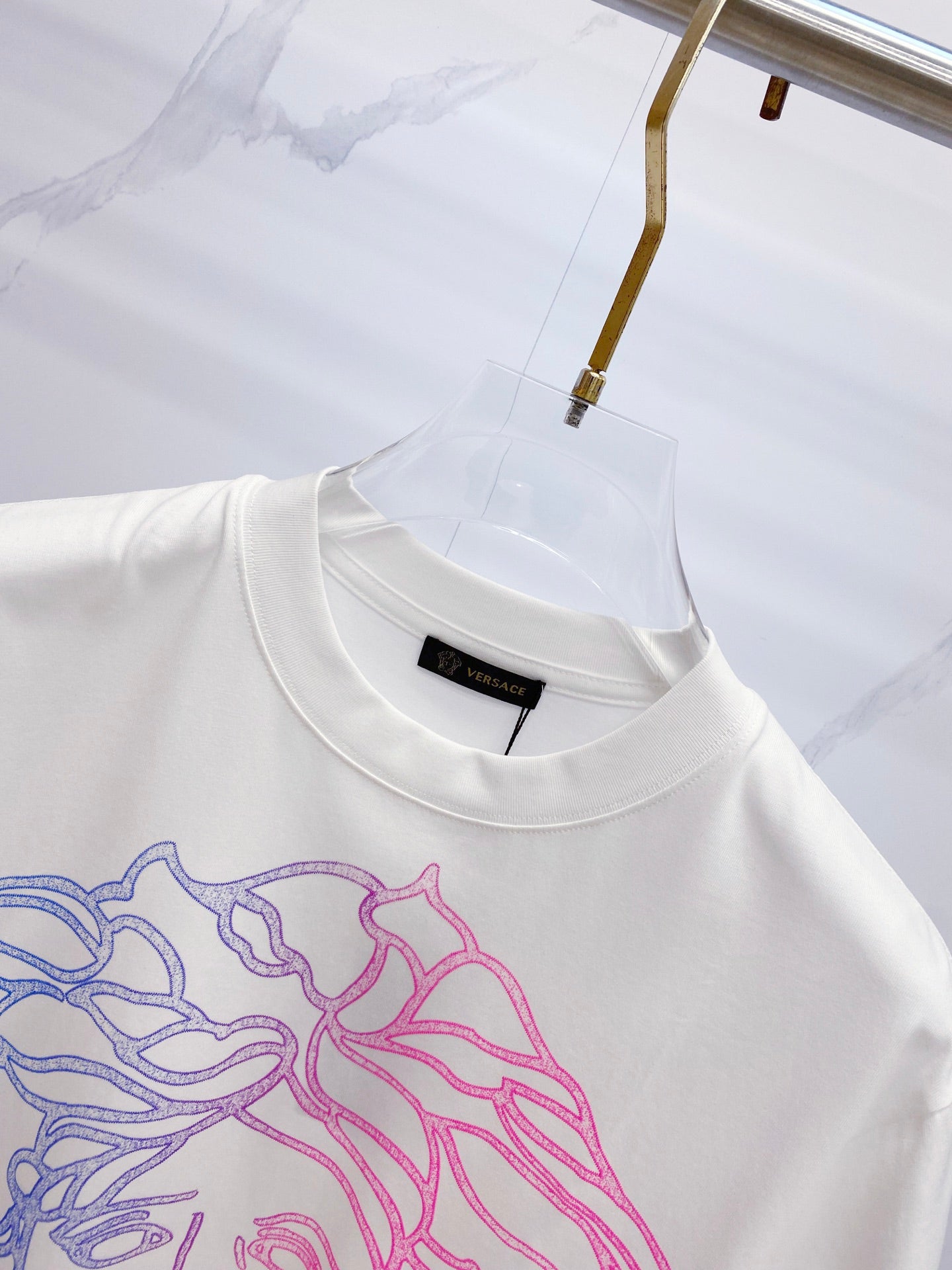 White crewneck T-shirt with blue and pink Medusa graphic at chest