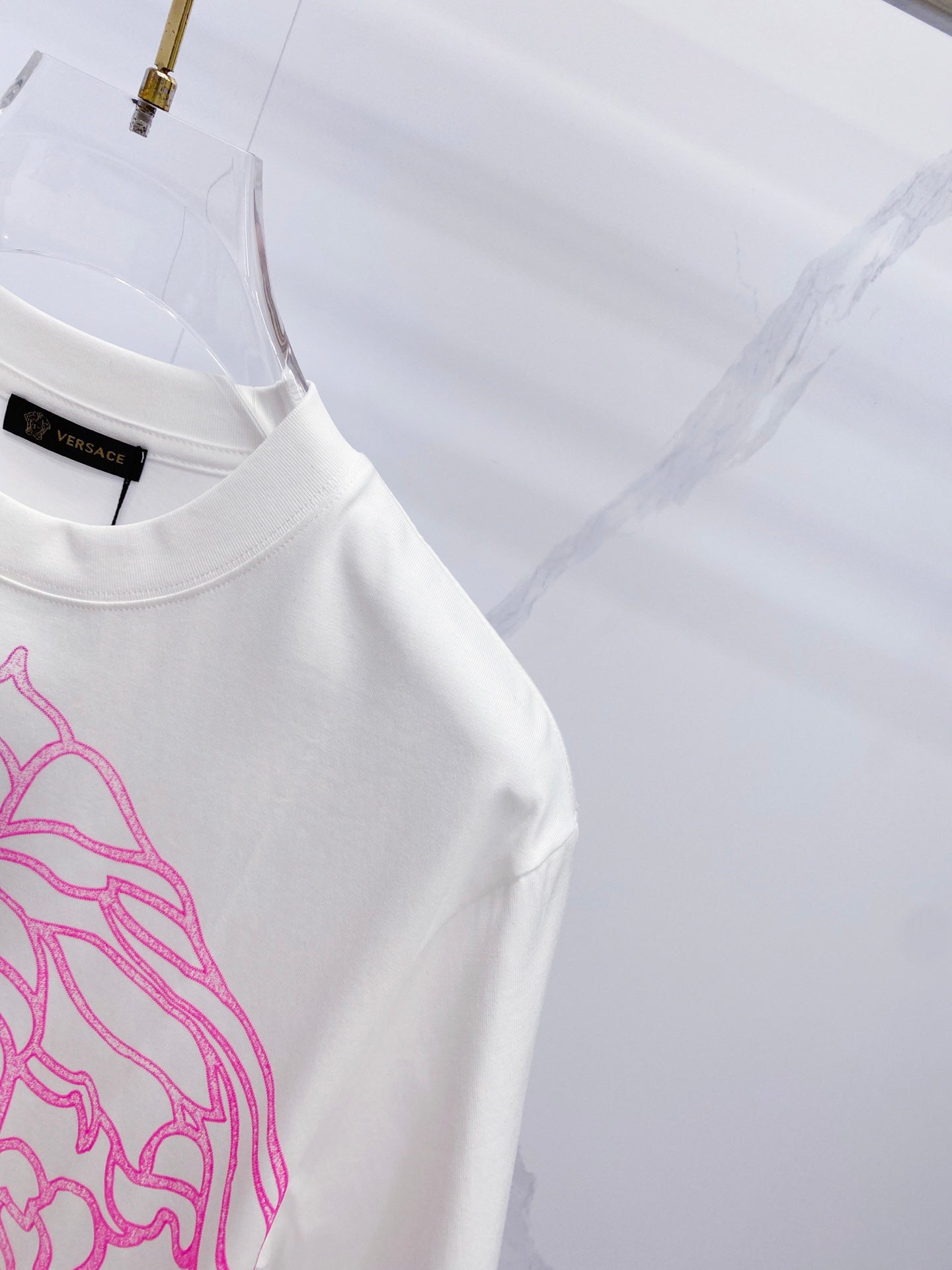 White crewneck T-shirt with black logo tag and blue/pink graphic