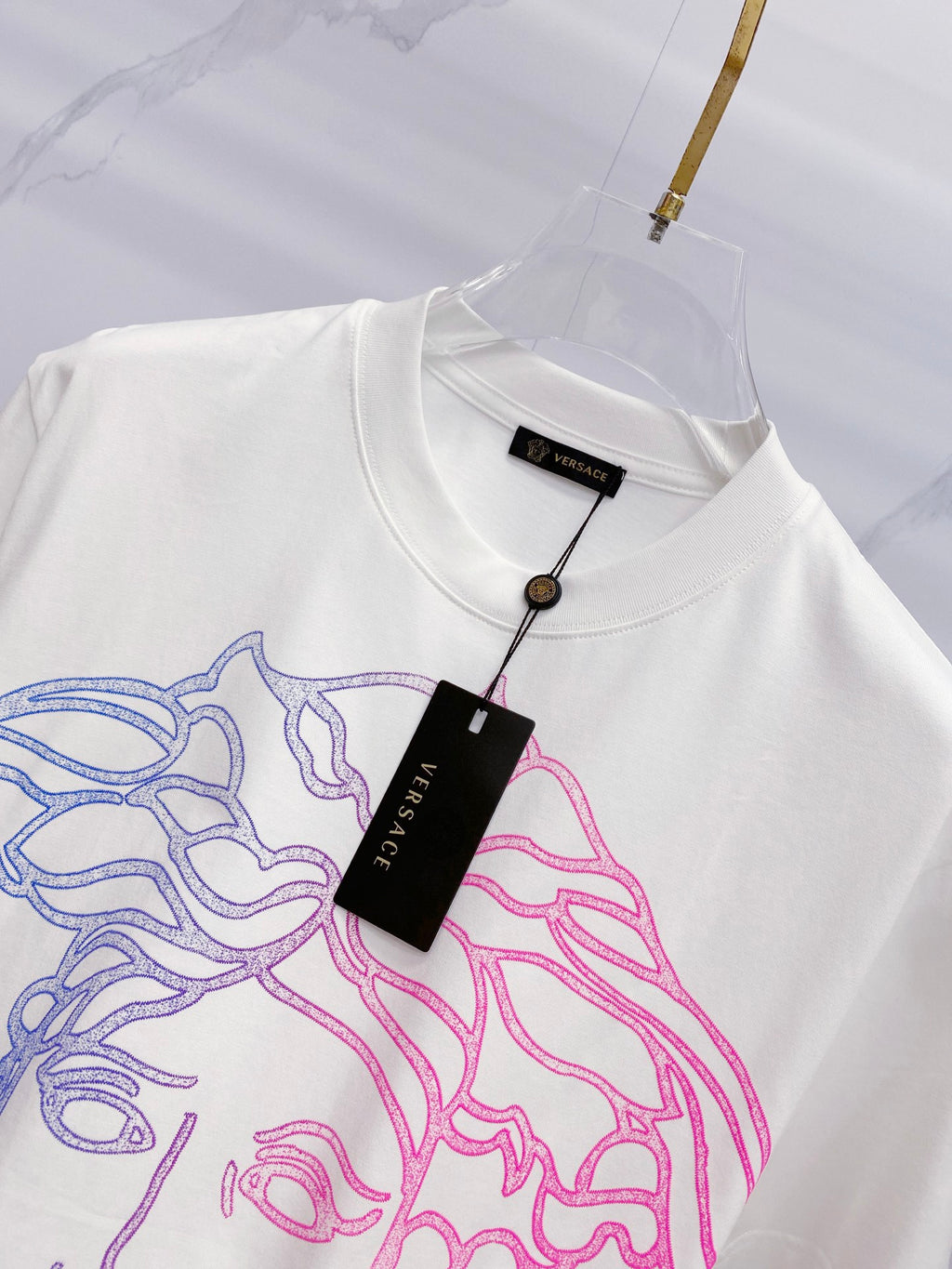 White crewneck T-shirt with hanging label and blue/pink Medusa graphic