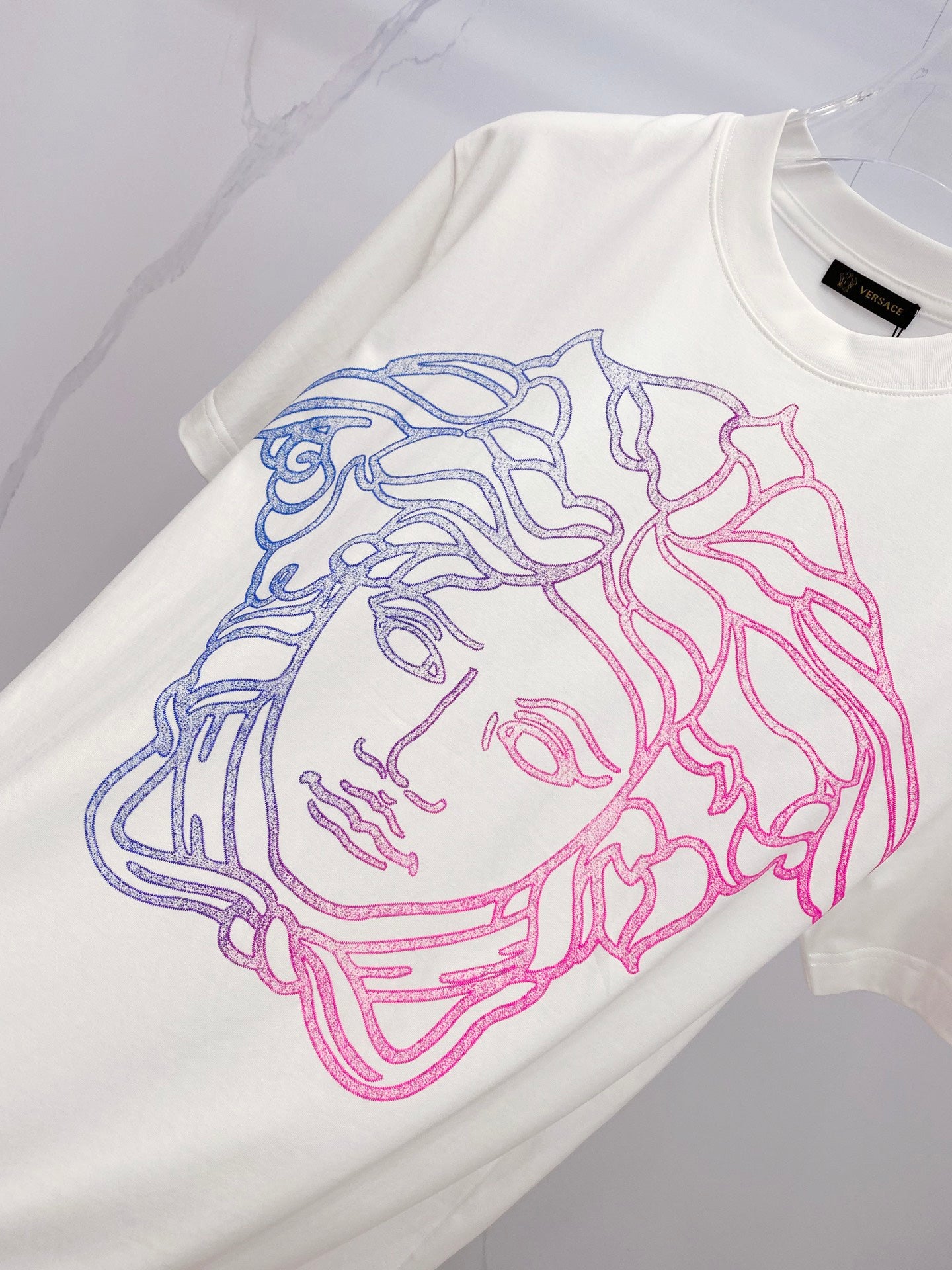White T-shirt with large blue and pink Medusa face graphic on front