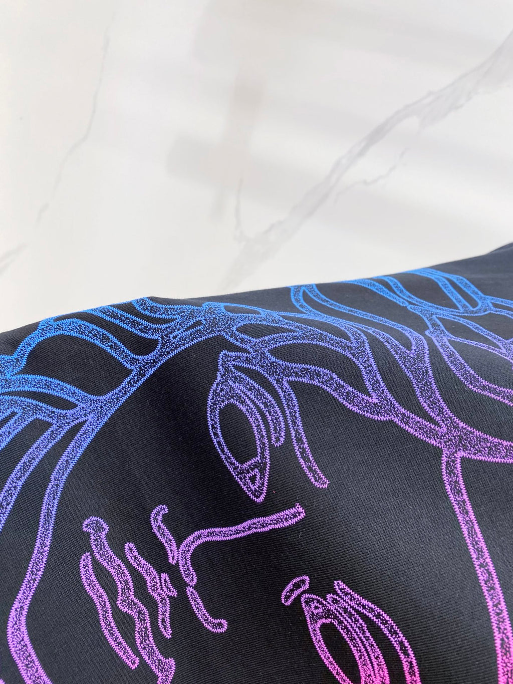 Versace T-shirt close-up of shoulder graphic in blue and purple on dark navy
