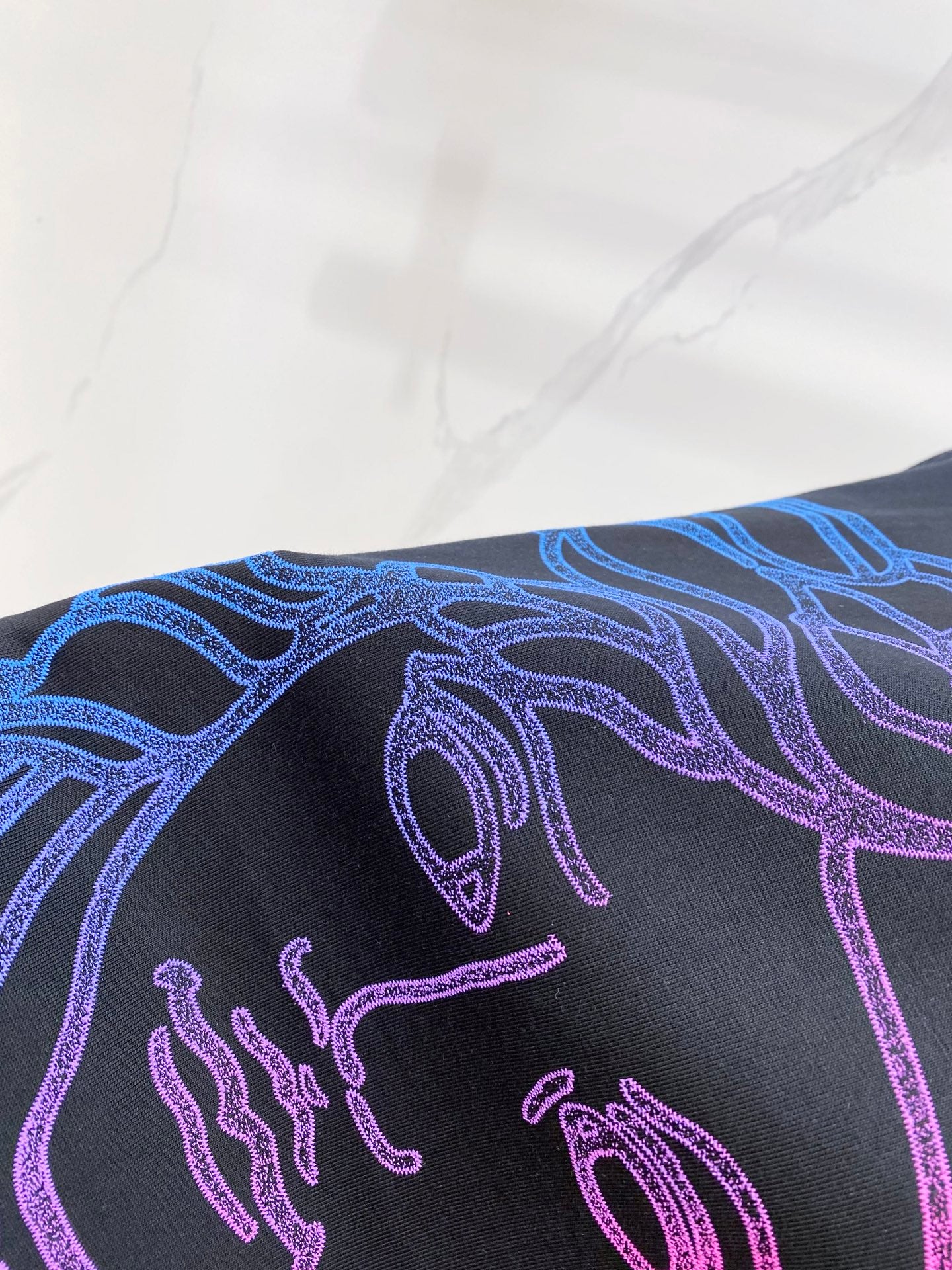 Versace T-shirt close-up of shoulder graphic in blue and purple on dark navy