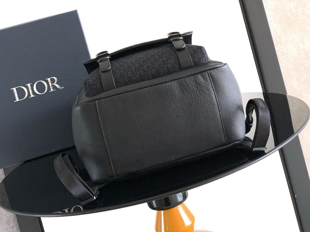 Dior mini backpack with pebbled leather, front pocket, top handle, and adjustable strap.