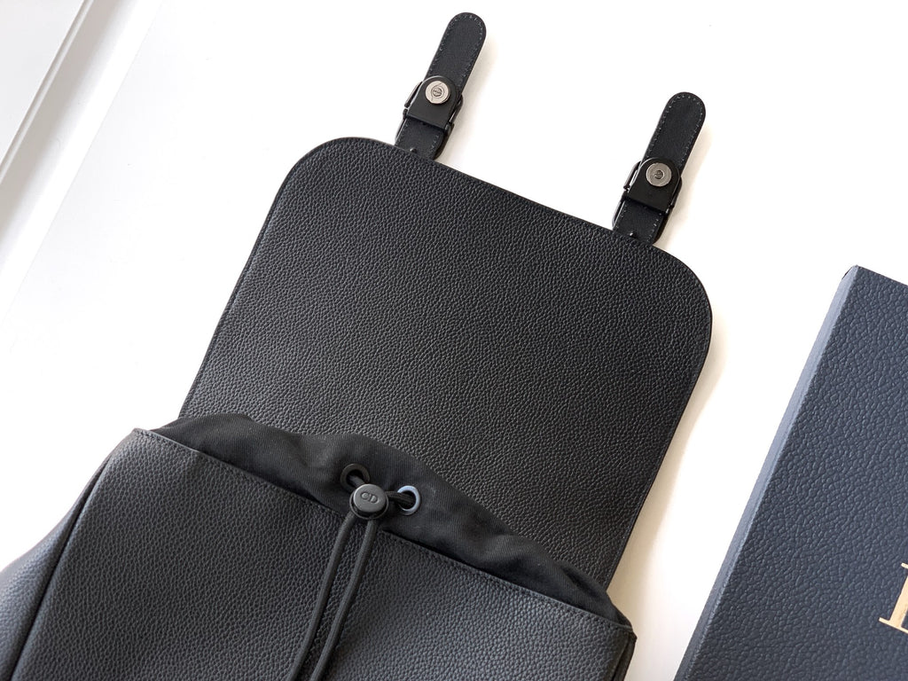 Dior backpack top section with textured leather, drawstring closure, and black webbing straps.