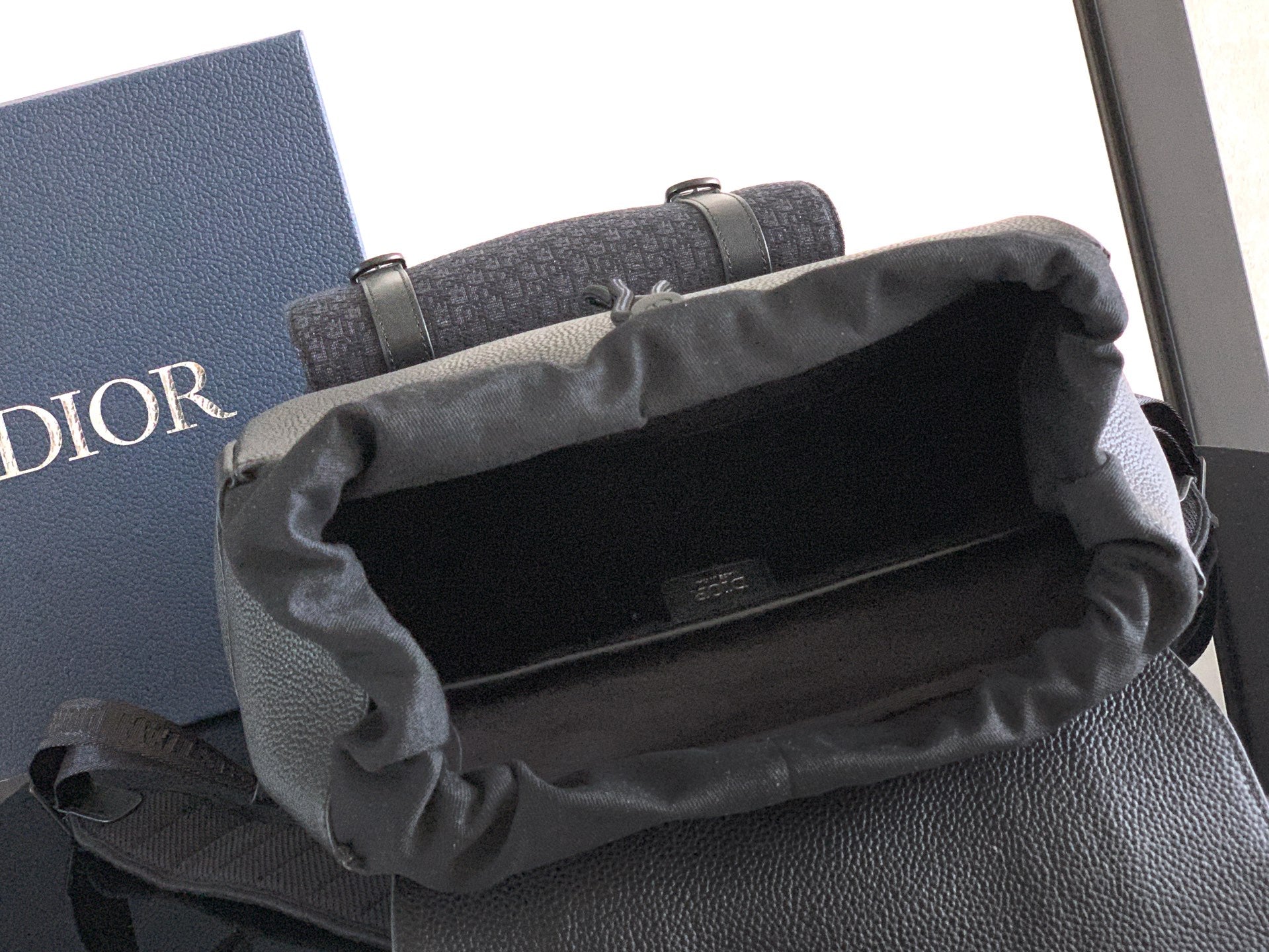 Dior backpack with open top and fabric lining, showing the main compartment interior.
