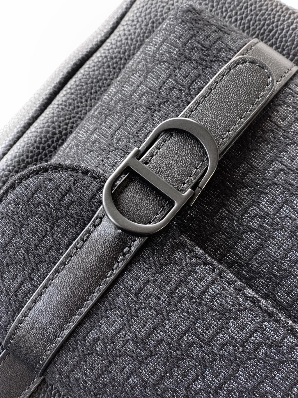 Dior backpack bag close-up of metal D-ring buckle on textured strap