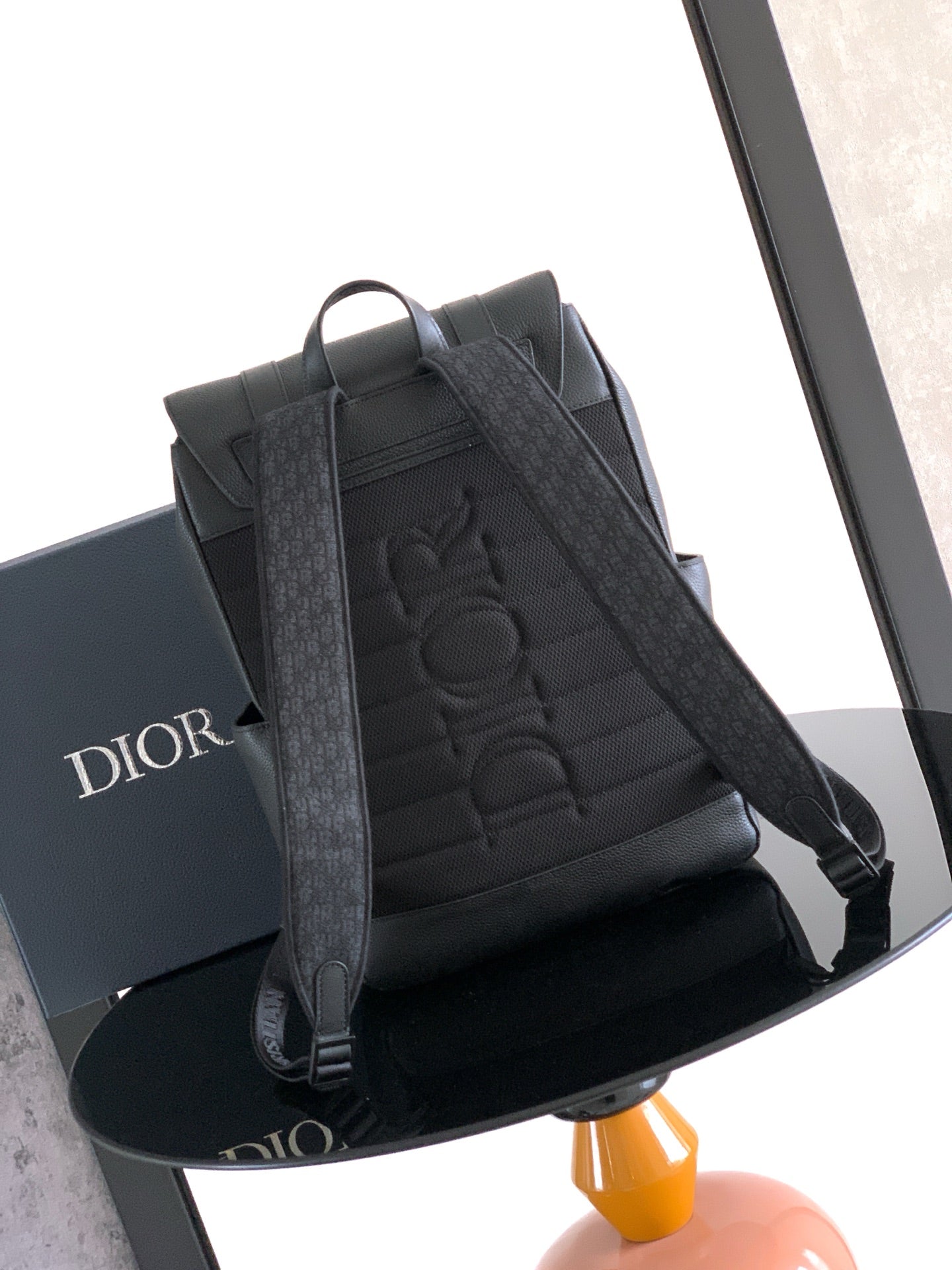 Dior backpack with embossed logo on front panel and adjustable shoulder straps, dark leather.