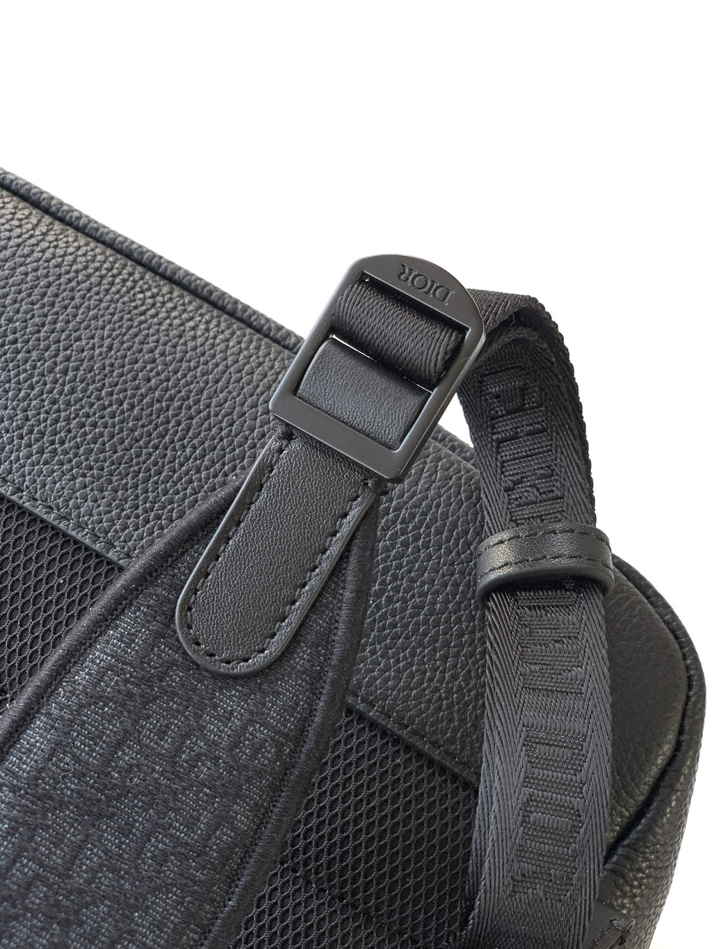 Dior backpack side close-up with logo-printed strap tab and stitched webbing.