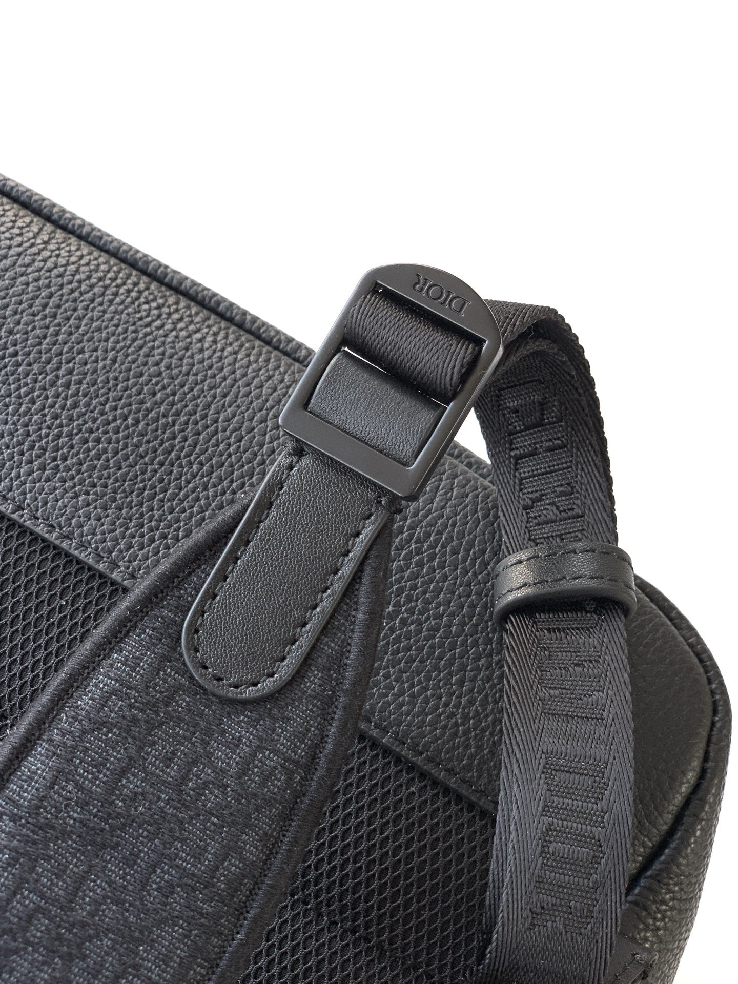Dior backpack side close-up with logo-printed strap tab and stitched webbing.