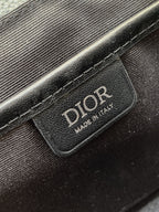 Dior bag leather patch with “DIOR” logo on dark textured fabric.