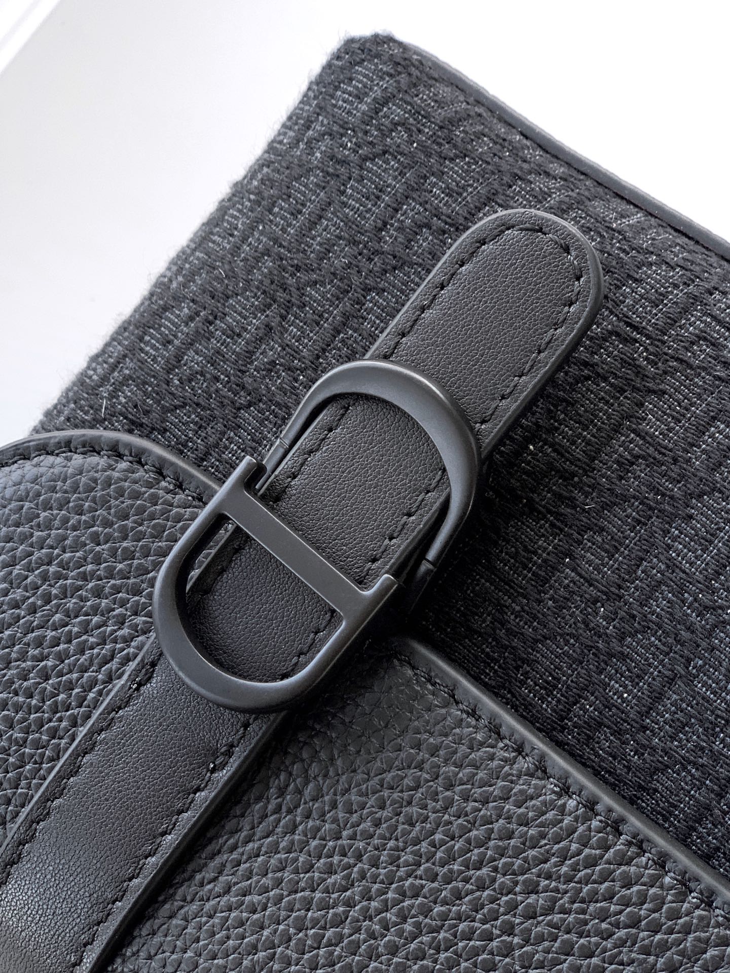 Dior bag close-up of dark gray fabric strap with gray buckle and leather trim edge.
