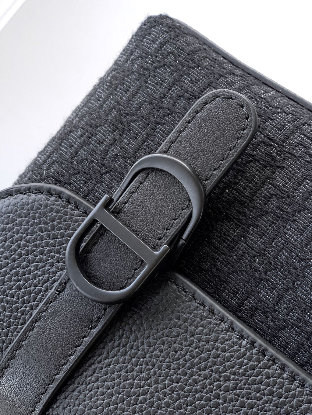 Dior bag strap close-up with oval buckle, dark grained leather detail