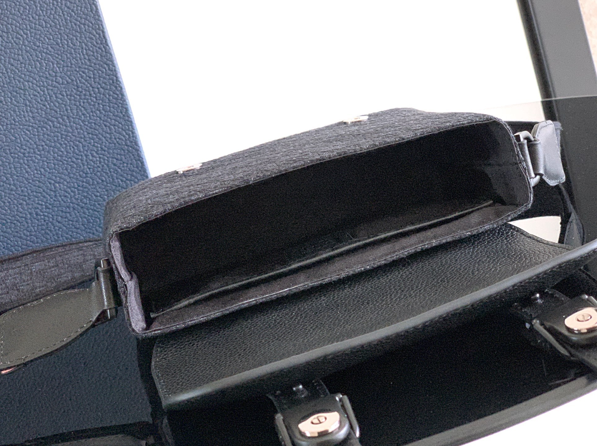 Dior bag interior view with open flap, dark lining, and metal snap hardware.