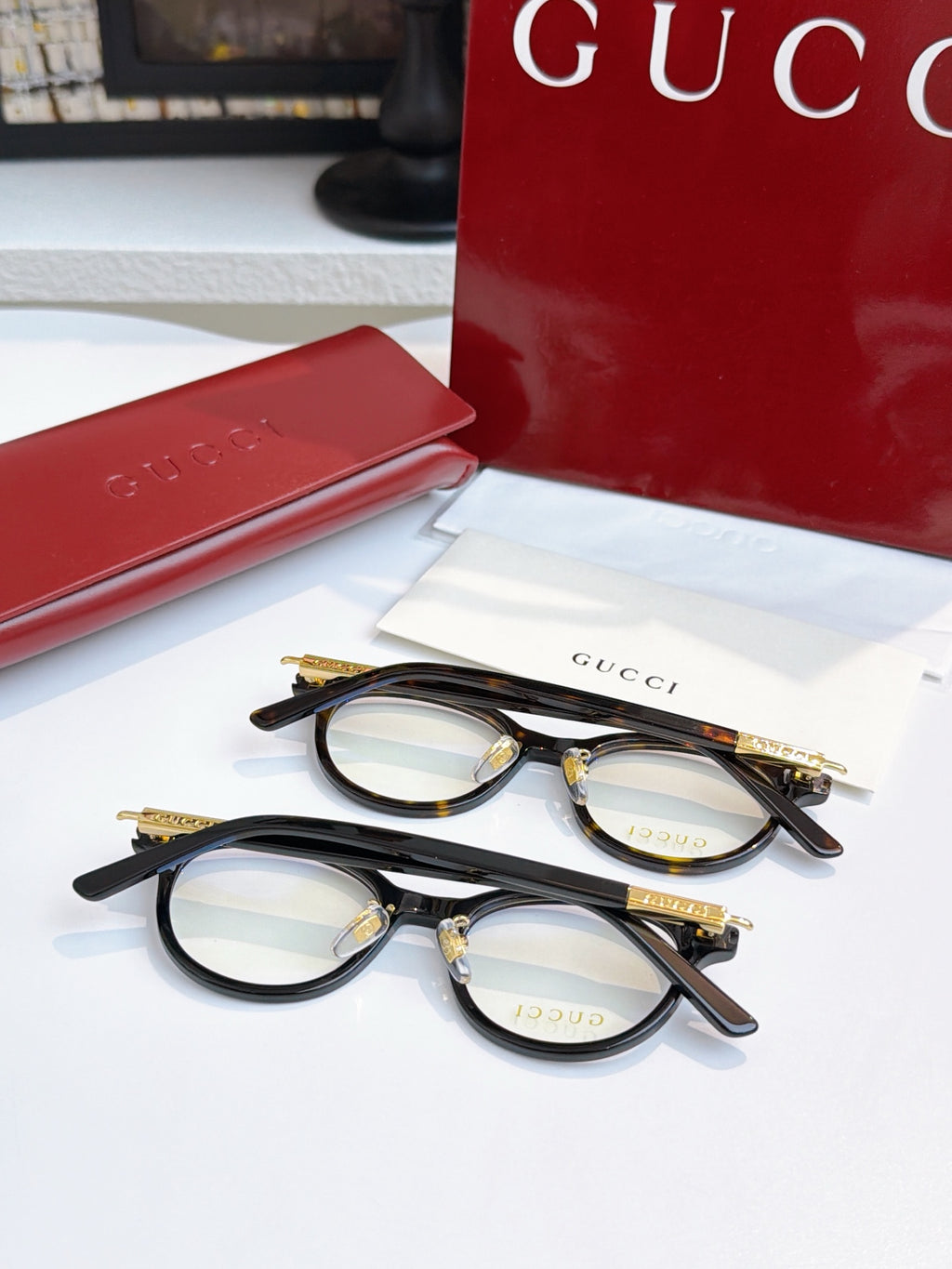 Gucci eyeglasses, two black round pairs with blue-tinted lenses; gold logo temples