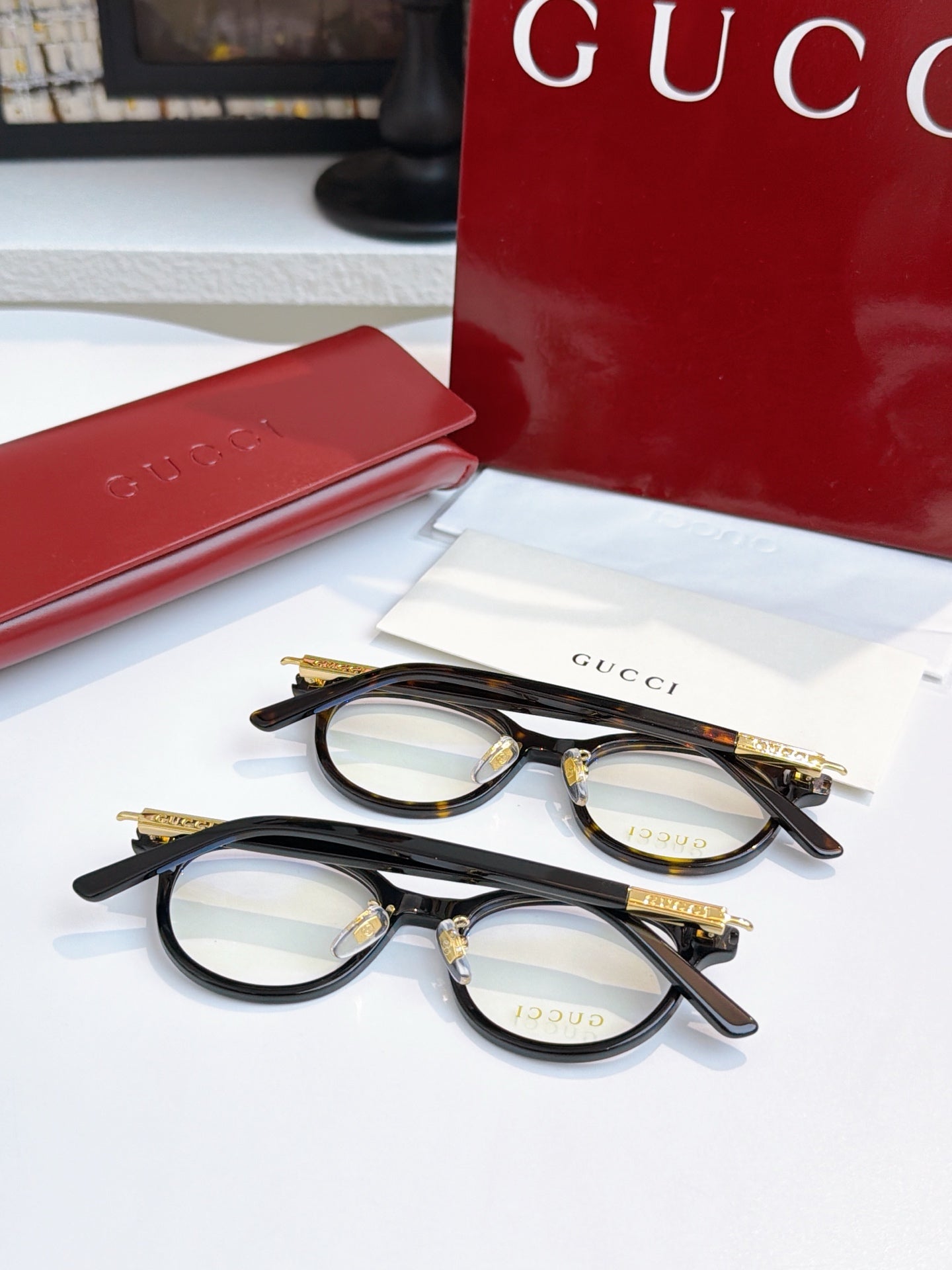 Gucci eyeglasses, two black round pairs with blue-tinted lenses; gold logo temples