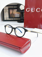 Gucci eyeglasses, black frames with blue lens tint; gold logo on temple