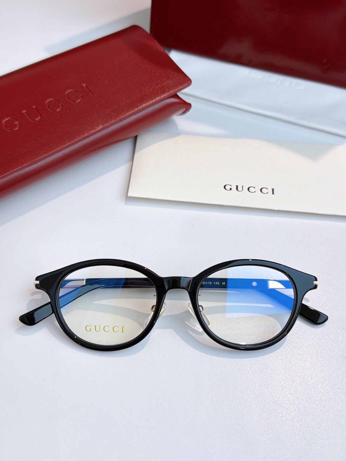 Gucci eyeglasses, black round frames with blue-tinted lenses and dark temple tips