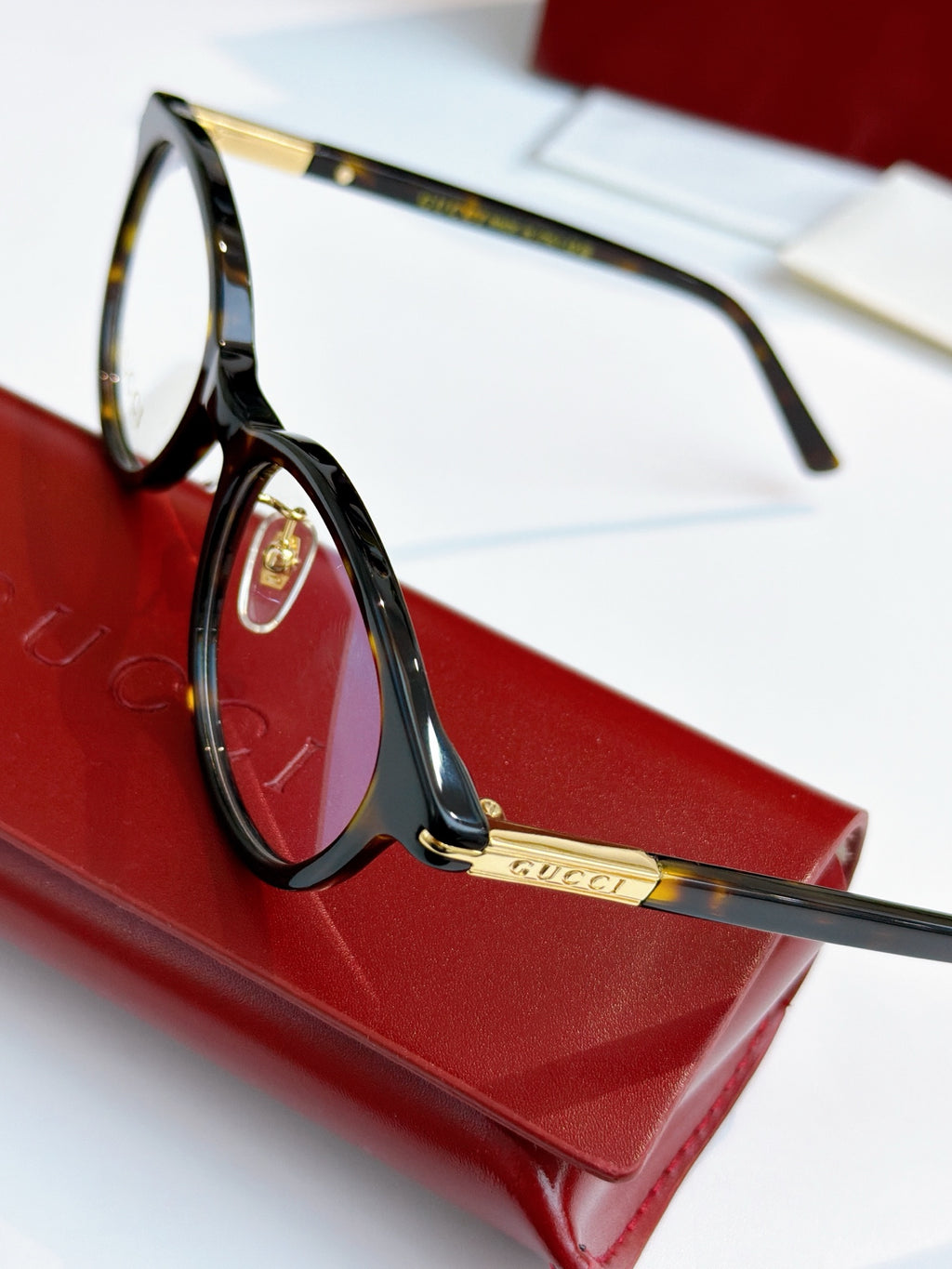 Gucci eyeglasses, black frame with blue lens tint; gold logo plate on temple