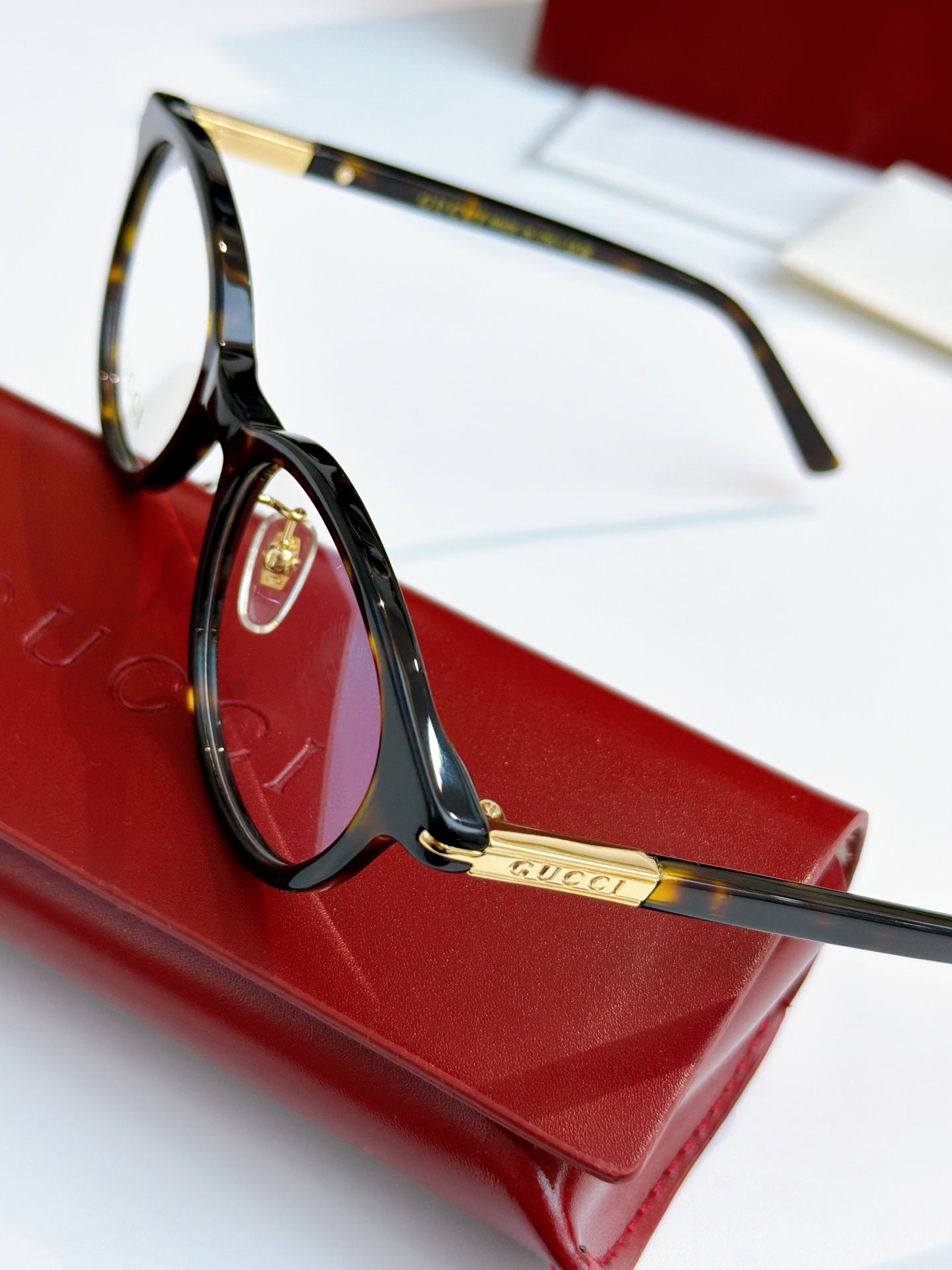 Gucci eyeglasses, black frame with blue lens tint; gold logo plate on temple