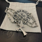 Silver cross pendant necklace resting on cream drawstring pouch on dark surface