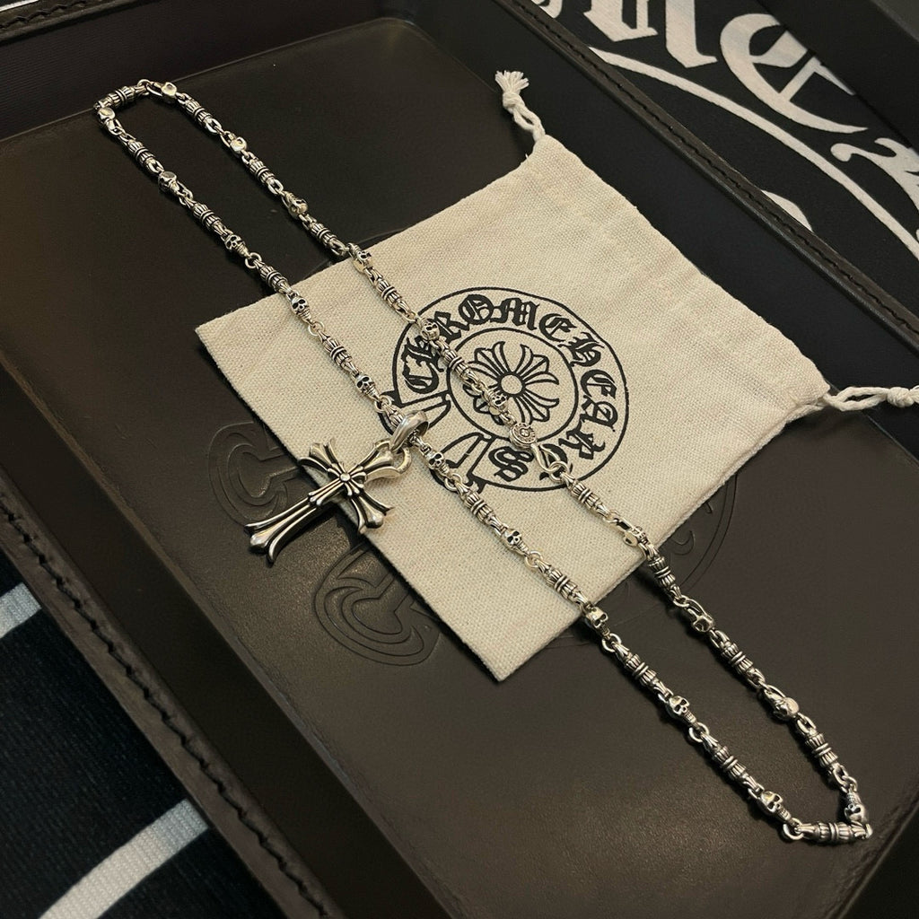 Silver cross pendant necklace on cream pouch atop dark leather case