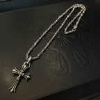 Silver cross pendant necklace detail on embossed dark box, close-up