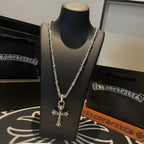 Silver cross pendant necklace with long beaded chain strands on black display bust