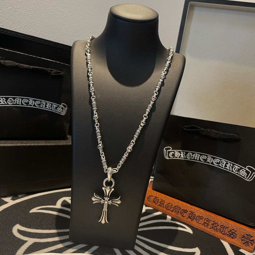 Silver cross pendant necklace with long beaded chain strands on black display bust