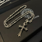 Silver cross pendant necklace and chain set on dark leather box with logo