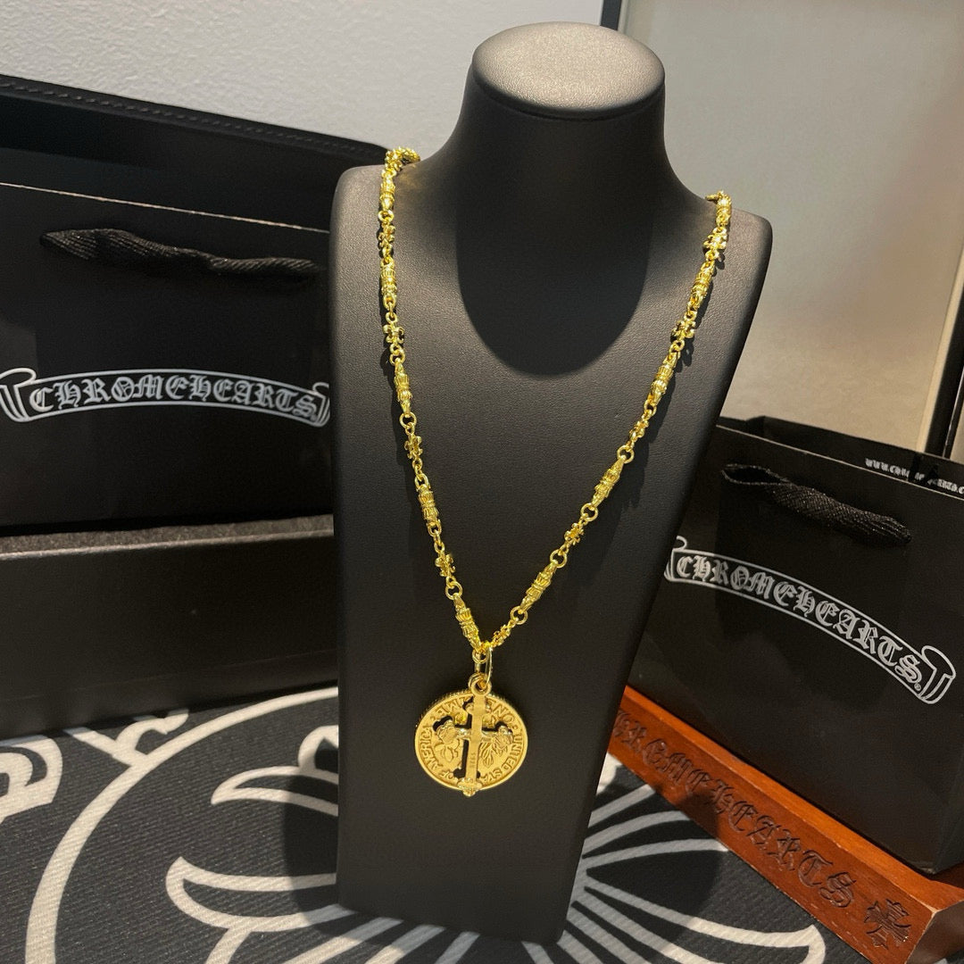 Gold-tone cross pendant necklace on black bust, with layered chain detail.