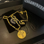 Gold-tone cross pendant necklace set on black tray with two round pendants.