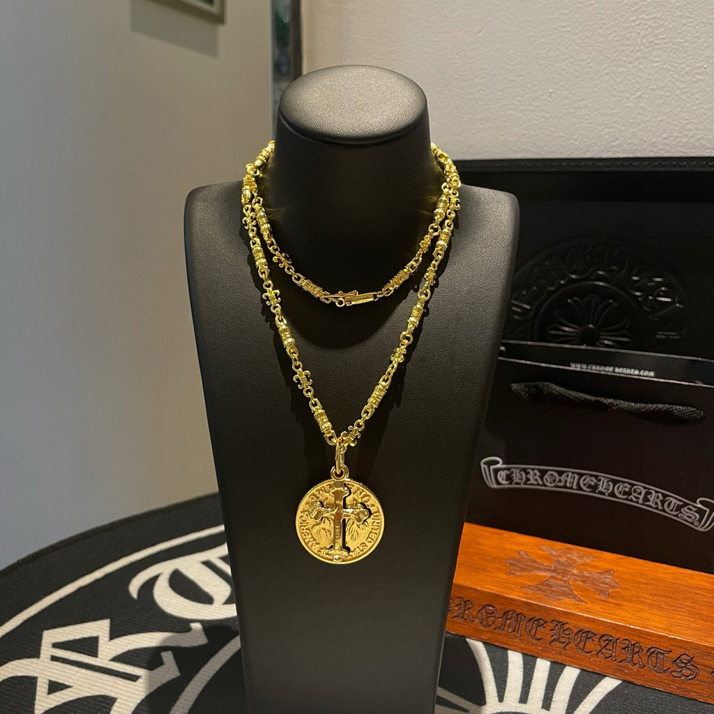 Gold-tone cross pendant necklace on black jewelry stand, front view.