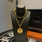 Gold-tone cross pendant necklace on black jewelry stand, front view.