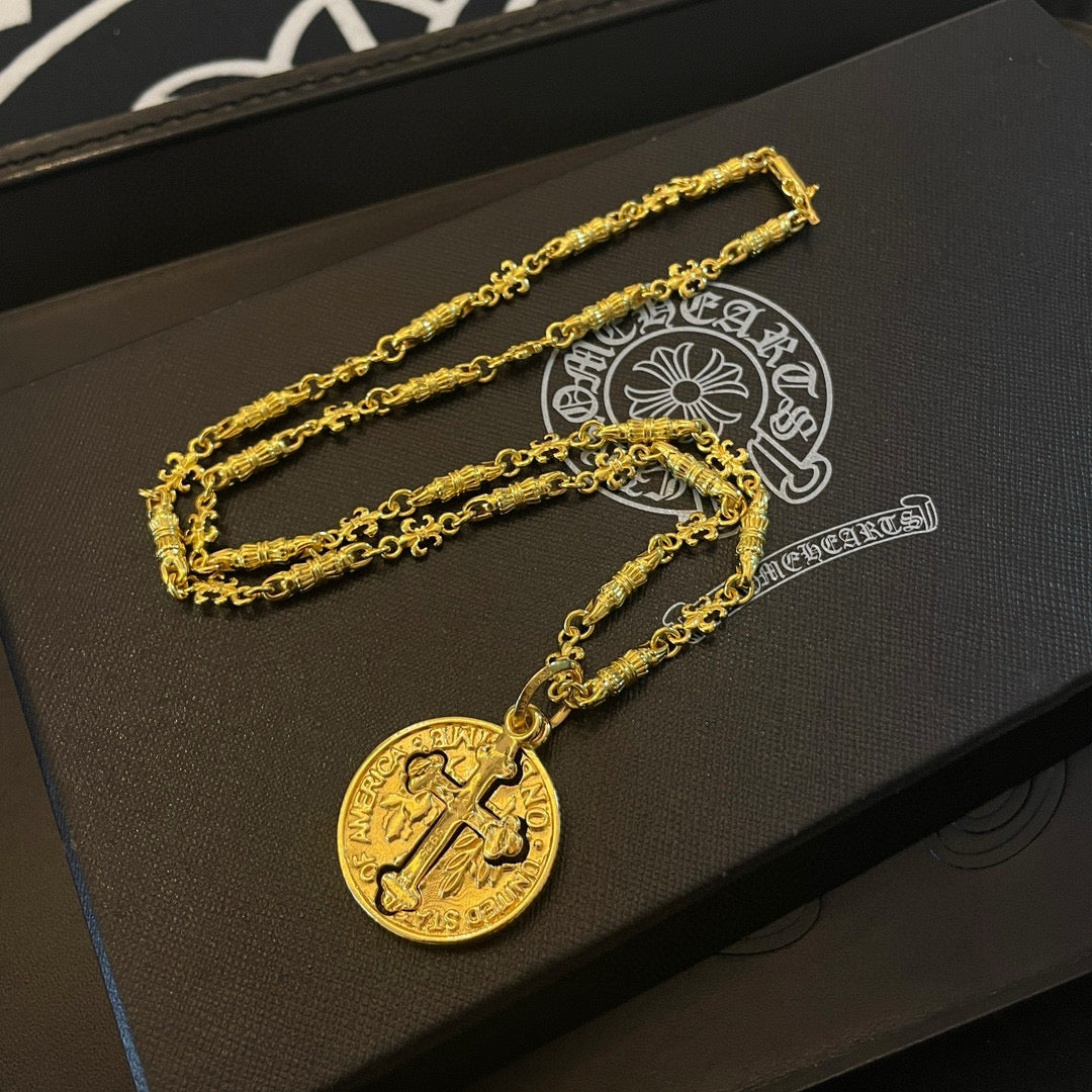 Gold-tone cross pendant necklace with round pendant on black jewelry box base.
